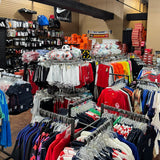 Clothing store interior with racks of shirts and sports equipment on display.