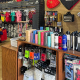 Store interior with sports merchandise including shirts, hats, and water bottles.